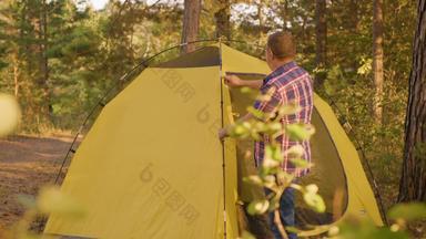 旅游男人。设置野营帐篷阳光明媚的森林旅行男人。检查旅游帐篷森林营地夏天森林徒步旅行概念